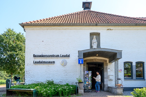Eine Frau betrachtet die Postkarten, die draußen vor dem Eingang des Besucherzentrums von Leudal / des Leudal-Museums liegen.