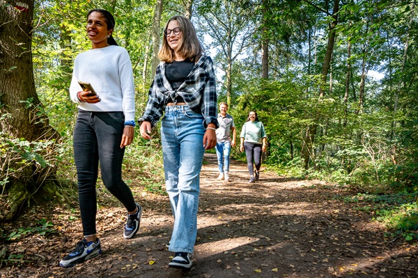 Zwei Kinder schlendern gemütlich einen Waldweg im Naturschutzgebiet Leudal entlang, im Hintergrund ihre Eltern.